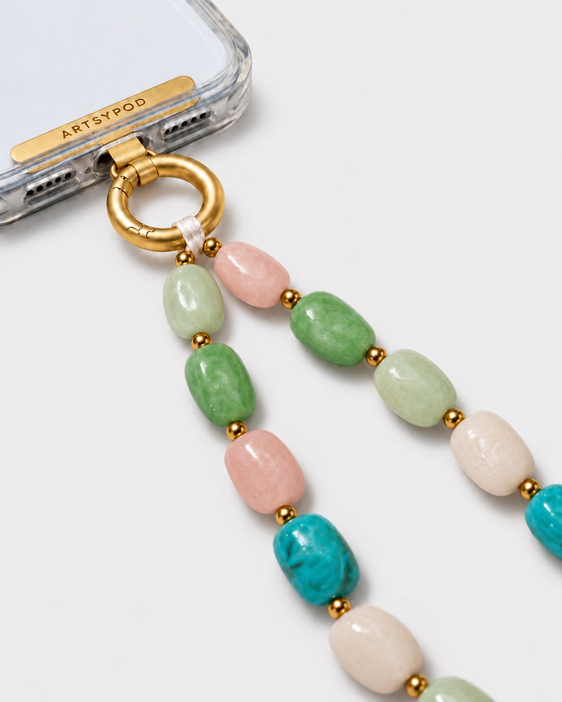 Close-up of ARTSYPOD pastel multicolour marbled beaded phone wristlet with gold-tone hardware attached to a clear phone case