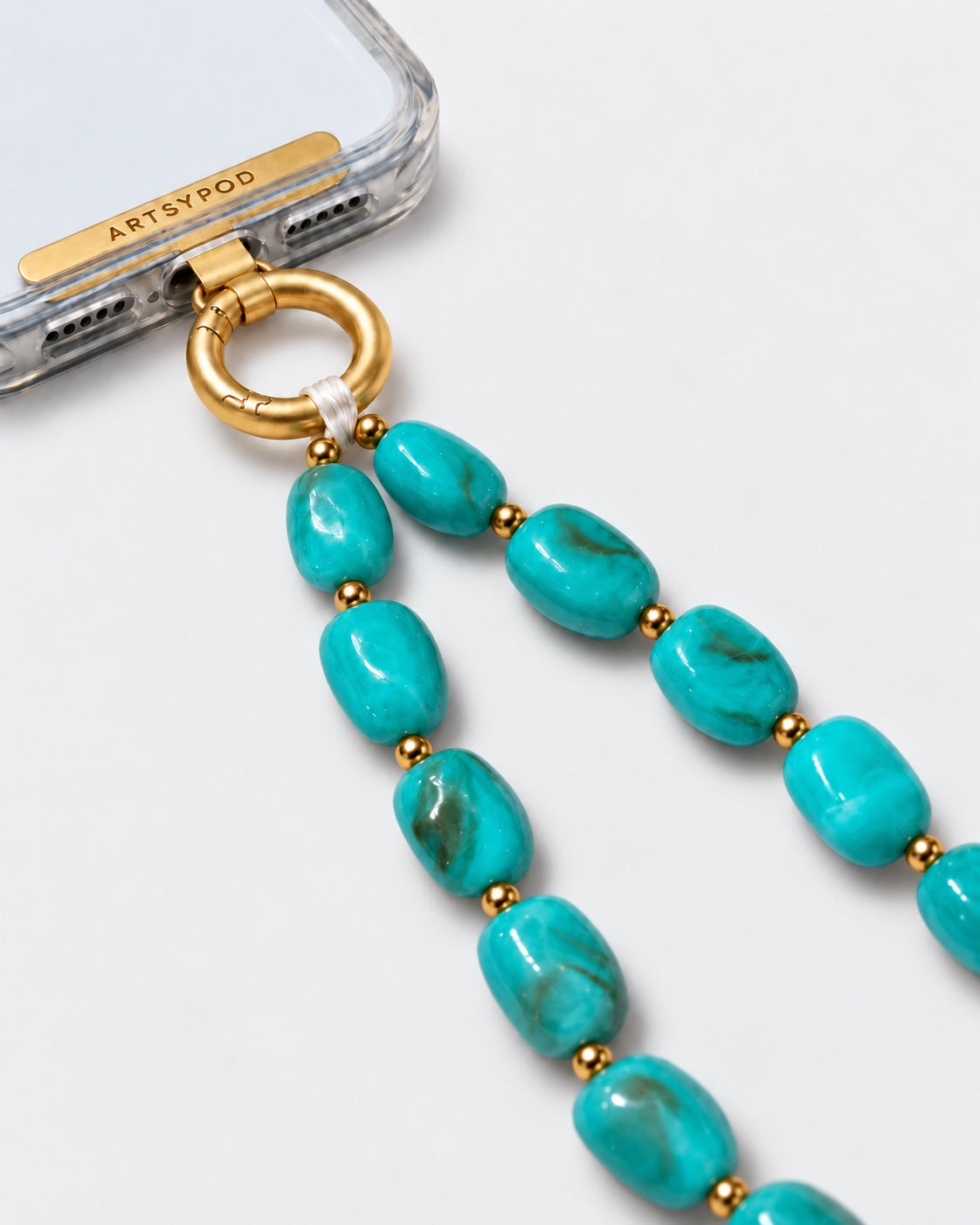 Close-up of ARTSYPOD turquoise blue-green marbled beaded phone wristlet with gold-tone hardware attached to a clear phone case